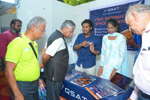 Visitors examining QSAT satellite kits at an exhibition stand